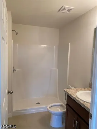 a bathroom with a granite countertop sink a toilet and shower