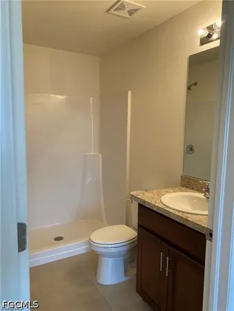 a bathroom with a granite countertop toilet a sink and a mirror