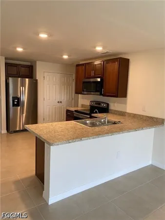 a view of kitchen with stainless steel appliances granite countertop refrigerator stove microwave and sink