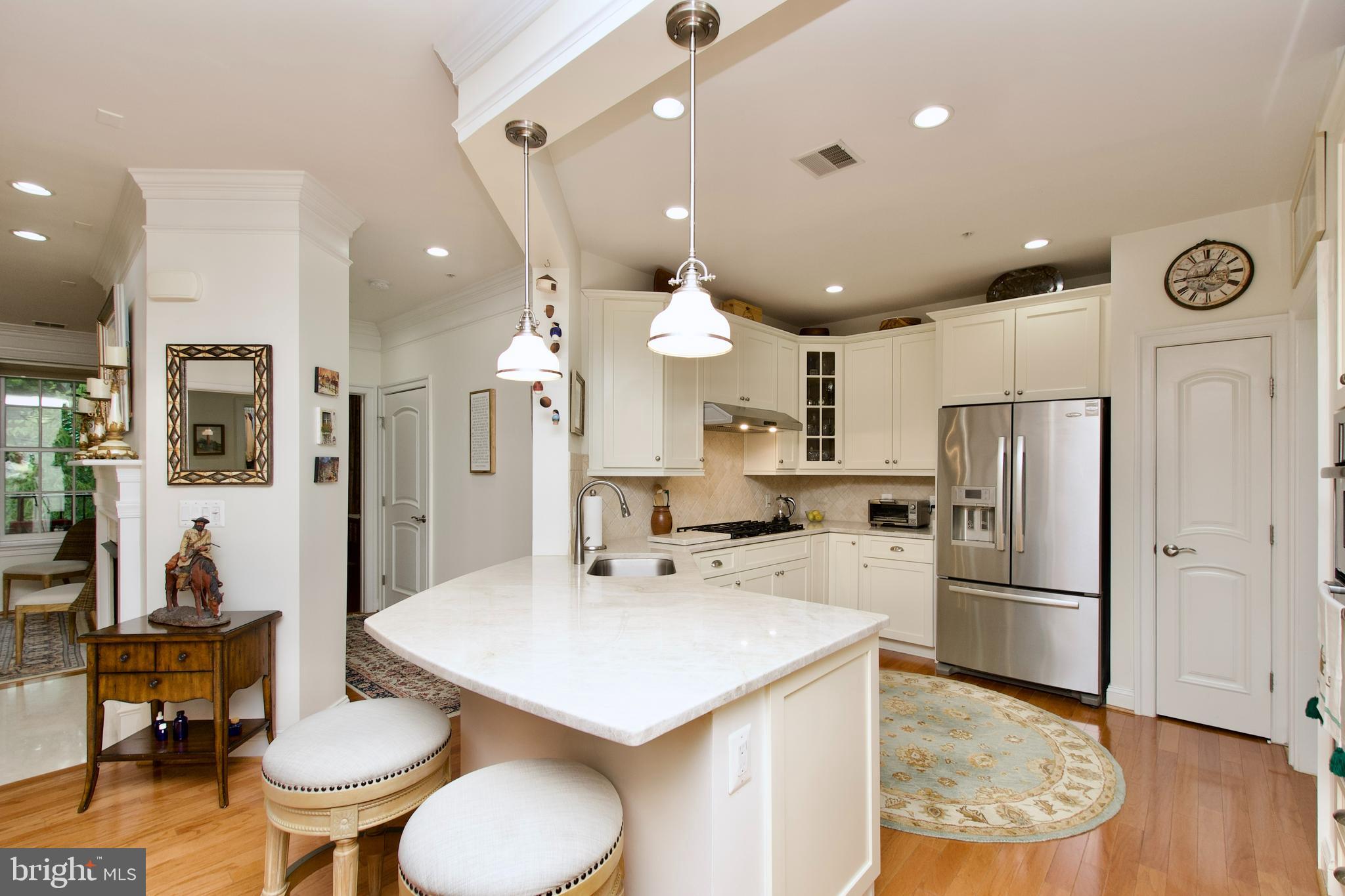 1781 Chain Bridge Road, Unit 302 McLean, VA 22102 - Photo 6 of 39 a kitchen with stainless steel appliances a refrigerator a sink dishwasher a dining table and chairs with wooden floor