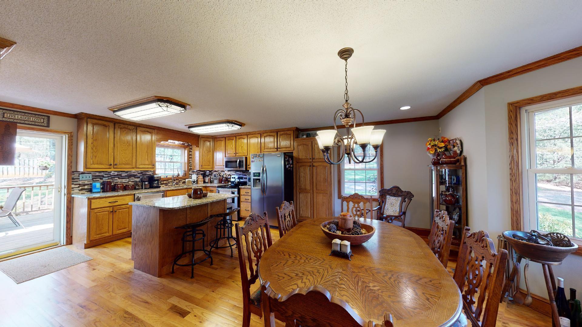 1534 Smith Road Forsyth, GA 31029 - Photo 6 of 25 a view of a dining room and livingroom with furniture wooden floor a rug a fireplace and a chandelier