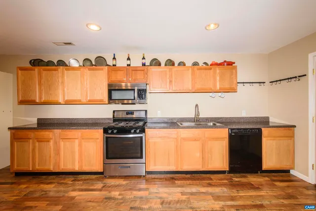 a kitchen with stainless steel appliances granite countertop a refrigerator a stove and a wooden floor