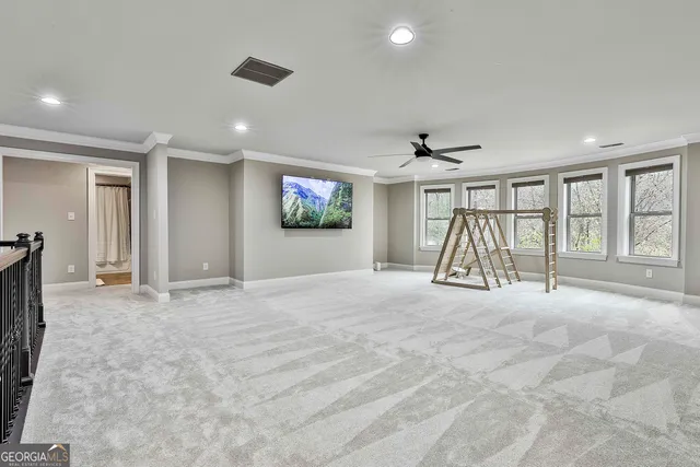 a view of an empty room with wooden floor and a ceiling fan