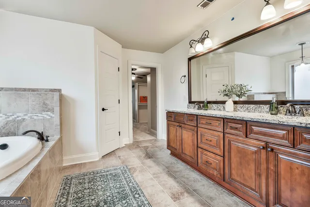 a bathroom with a granite countertop sink a toilet a mirror and shower