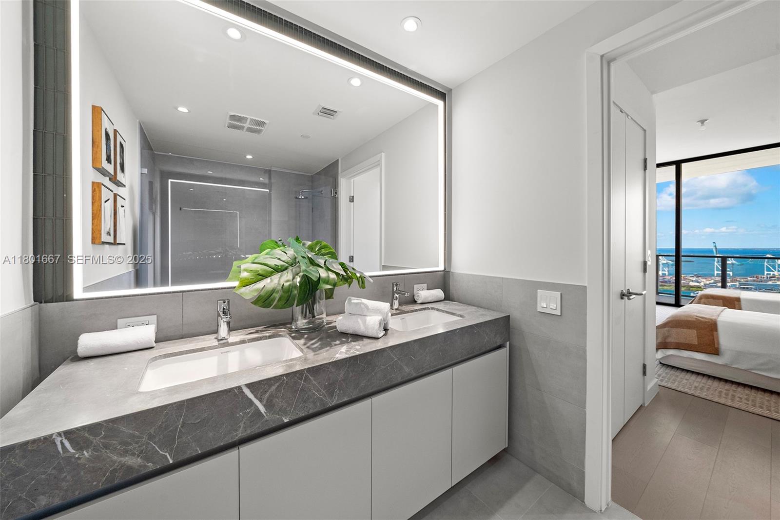 500 Alton Road, Unit 3602 Miami Beach, FL 33139 - Photo 24 of 33 a bathroom with a granite countertop sink a large mirror and a window