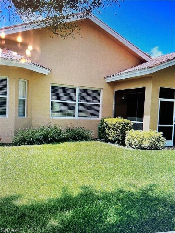 2132 Par Drive Naples, FL 34120 - Photo 14 of 17 View of property exterior with stucco siding, a yard, a tile roof, and a sunroom
