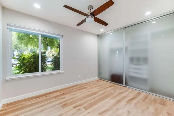 a view of empty room with wooden floor and fan