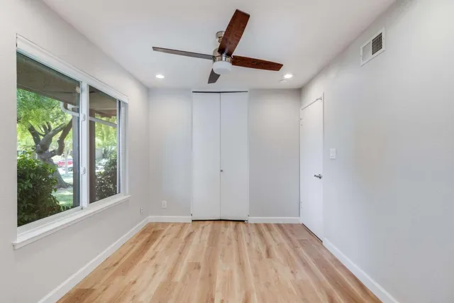 a view of empty room with wooden floor and fan