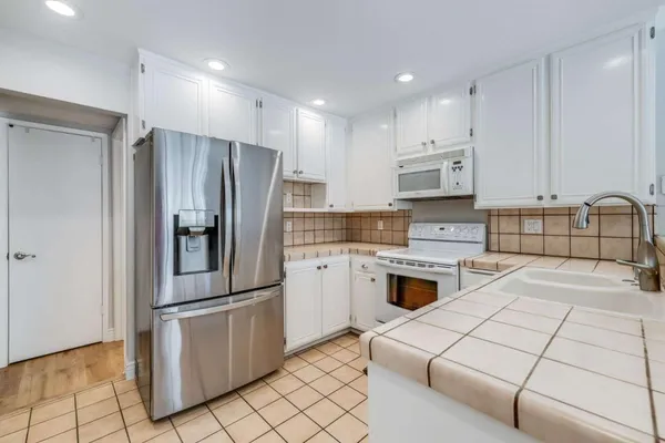 a kitchen with granite countertop a refrigerator stove and sink