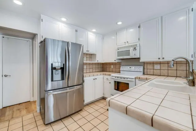 a kitchen with granite countertop a refrigerator stove and sink