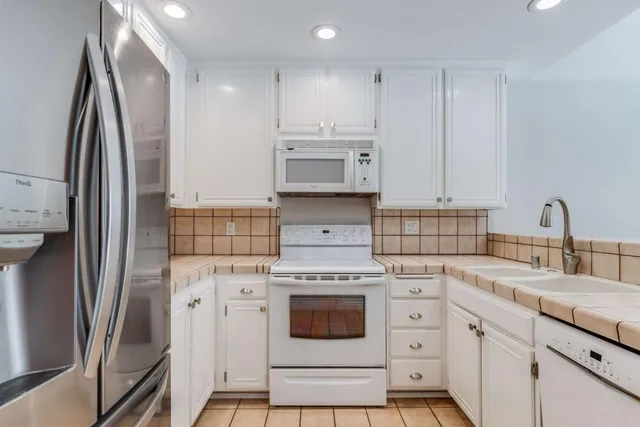a kitchen with white cabinets and stainless steel appliances