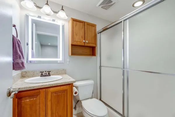 a bathroom with a granite countertop sink toilet and shower