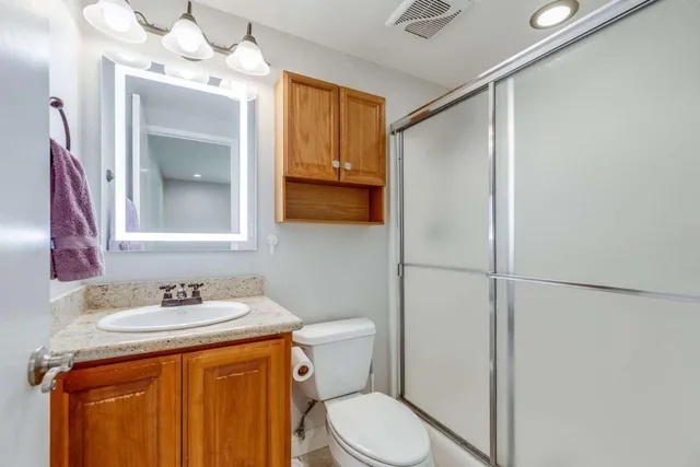 a bathroom with a granite countertop sink toilet and shower