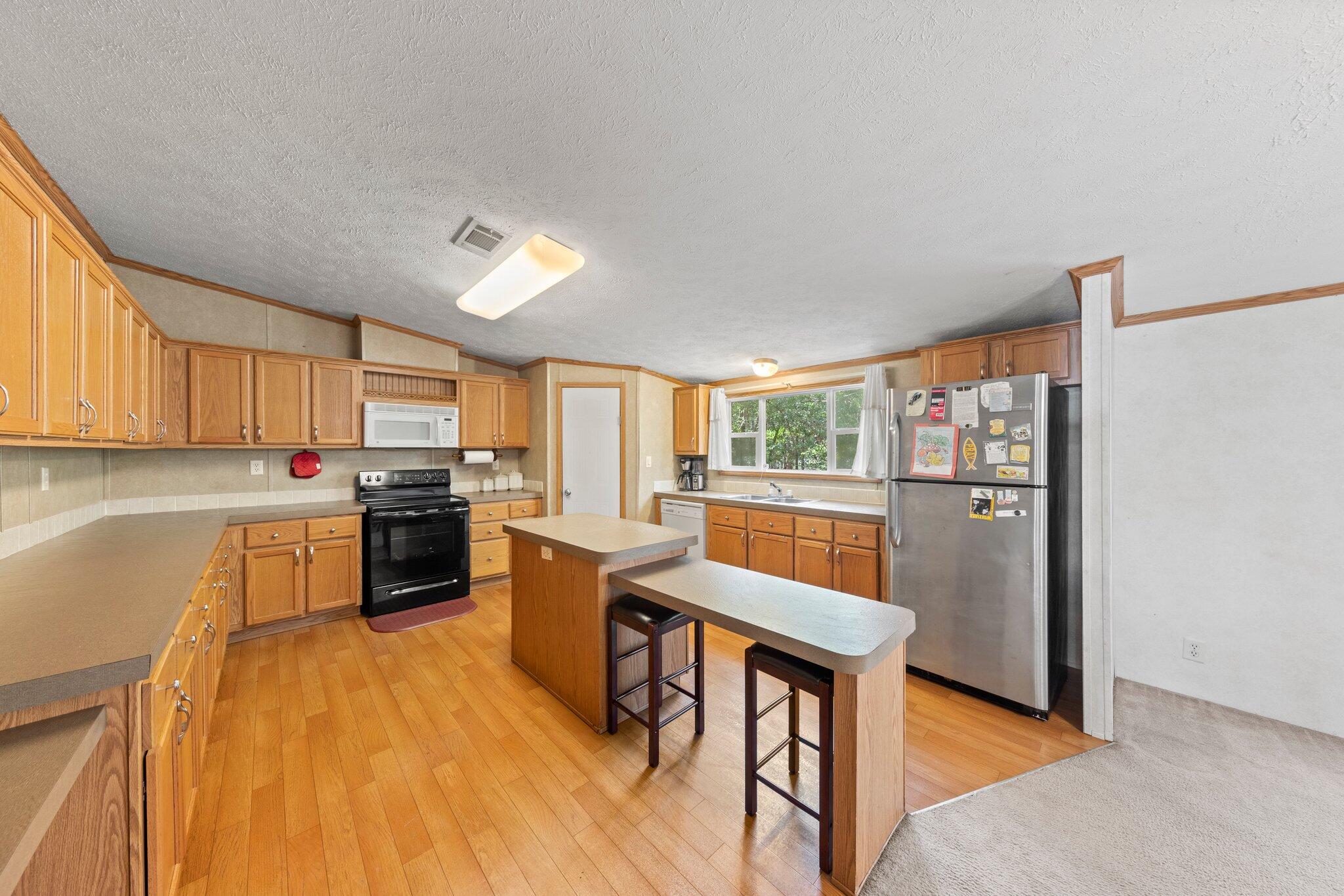 3943 Bambi Road Crestview, FL 32539 - Photo 17 of 36 a kitchen with stainless steel appliances granite countertop a refrigerator a stove top oven a sink dishwasher and white cabinets with wooden floor