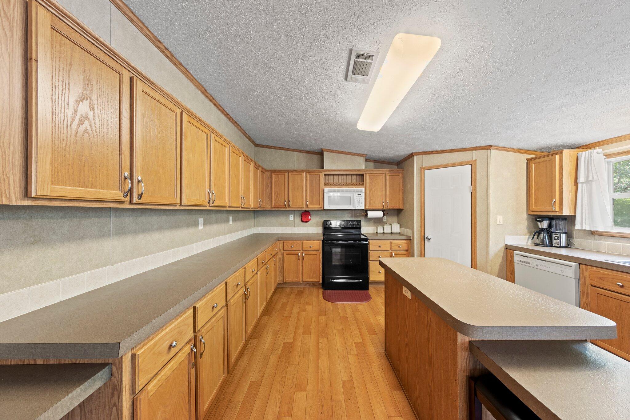 3943 Bambi Road Crestview, FL 32539 - Photo 18 of 36 a kitchen with stainless steel appliances granite countertop a stove a sink dishwasher and a refrigerator with wooden floor