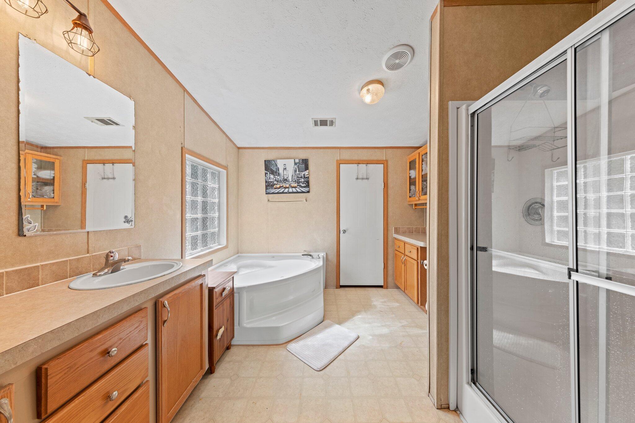 3943 Bambi Road Crestview, FL 32539 - Photo 9 of 36 a spacious bathroom with a double vanity sink a mirror and a bathtub