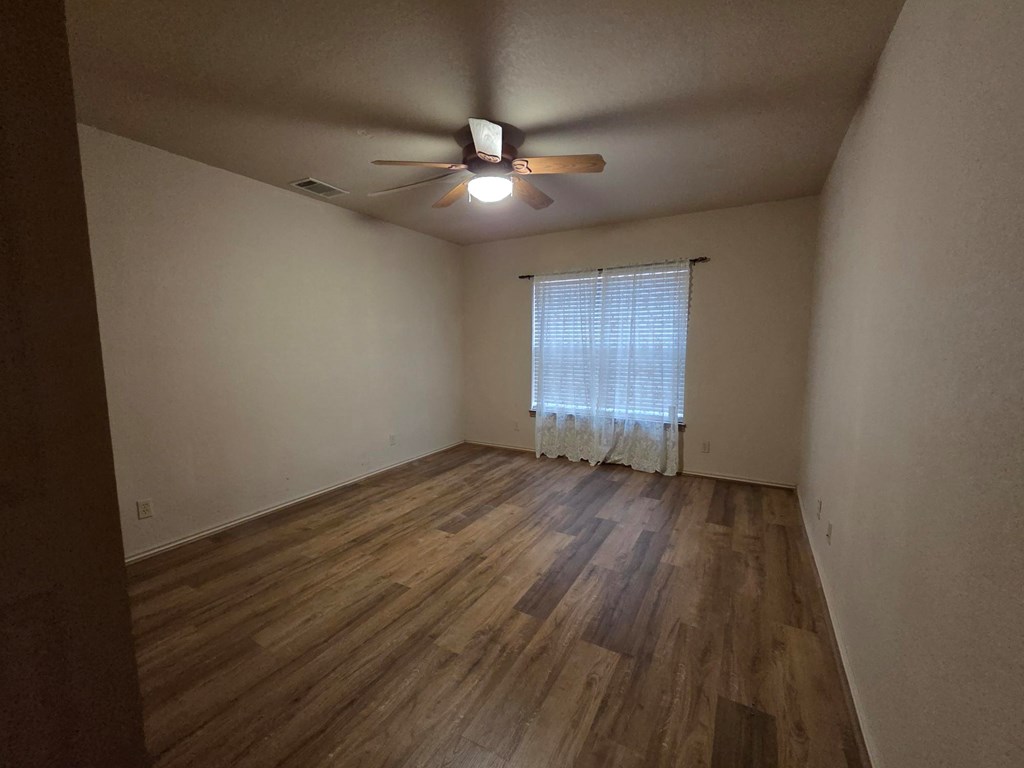 237 Green Oaks Loop Fredericksburg, TX 78624 - Photo 11 of 19 an empty room with wooden floor ceiling fan and windows