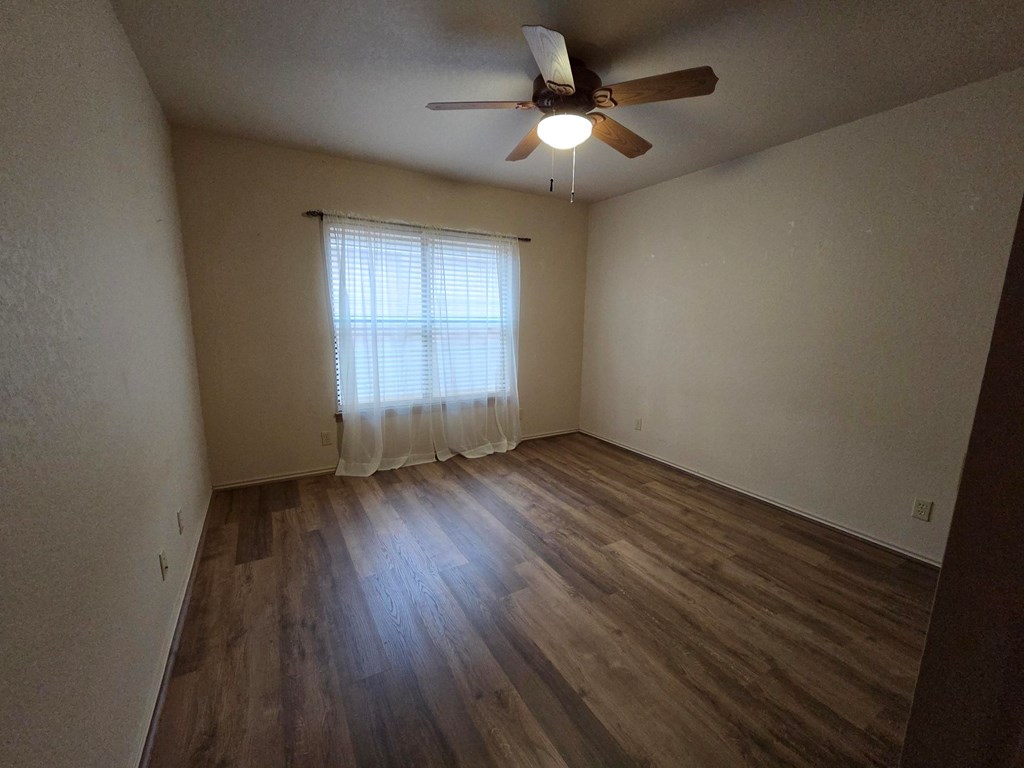 237 Green Oaks Loop Fredericksburg, TX 78624 - Photo 16 of 19 an empty room with wooden floor chandelier fan and windows