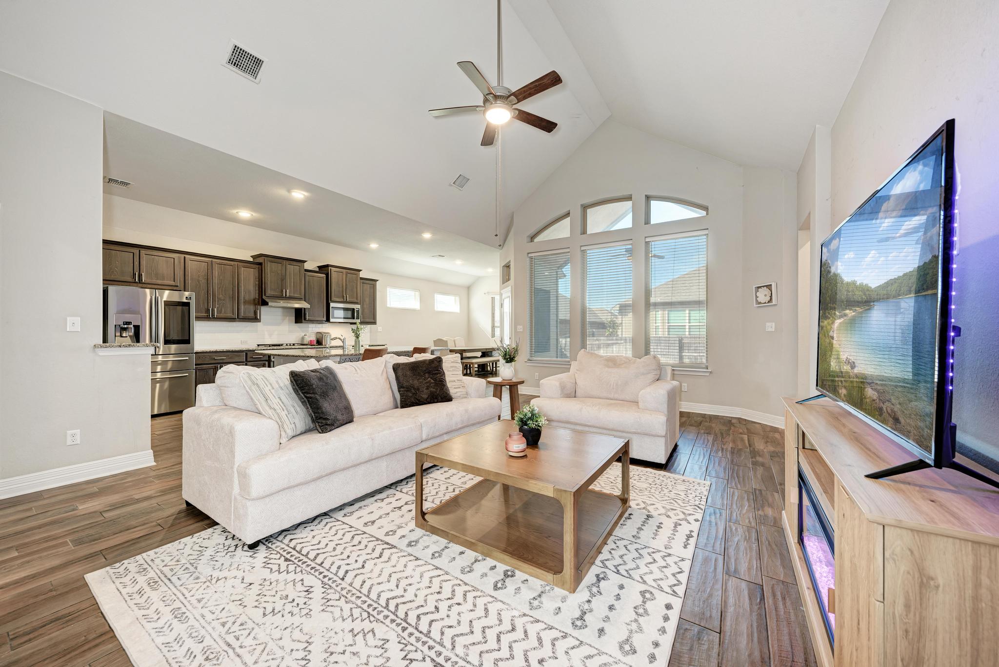 Living room with ceiling fan, a high ceiling, and dark wood-style floors
