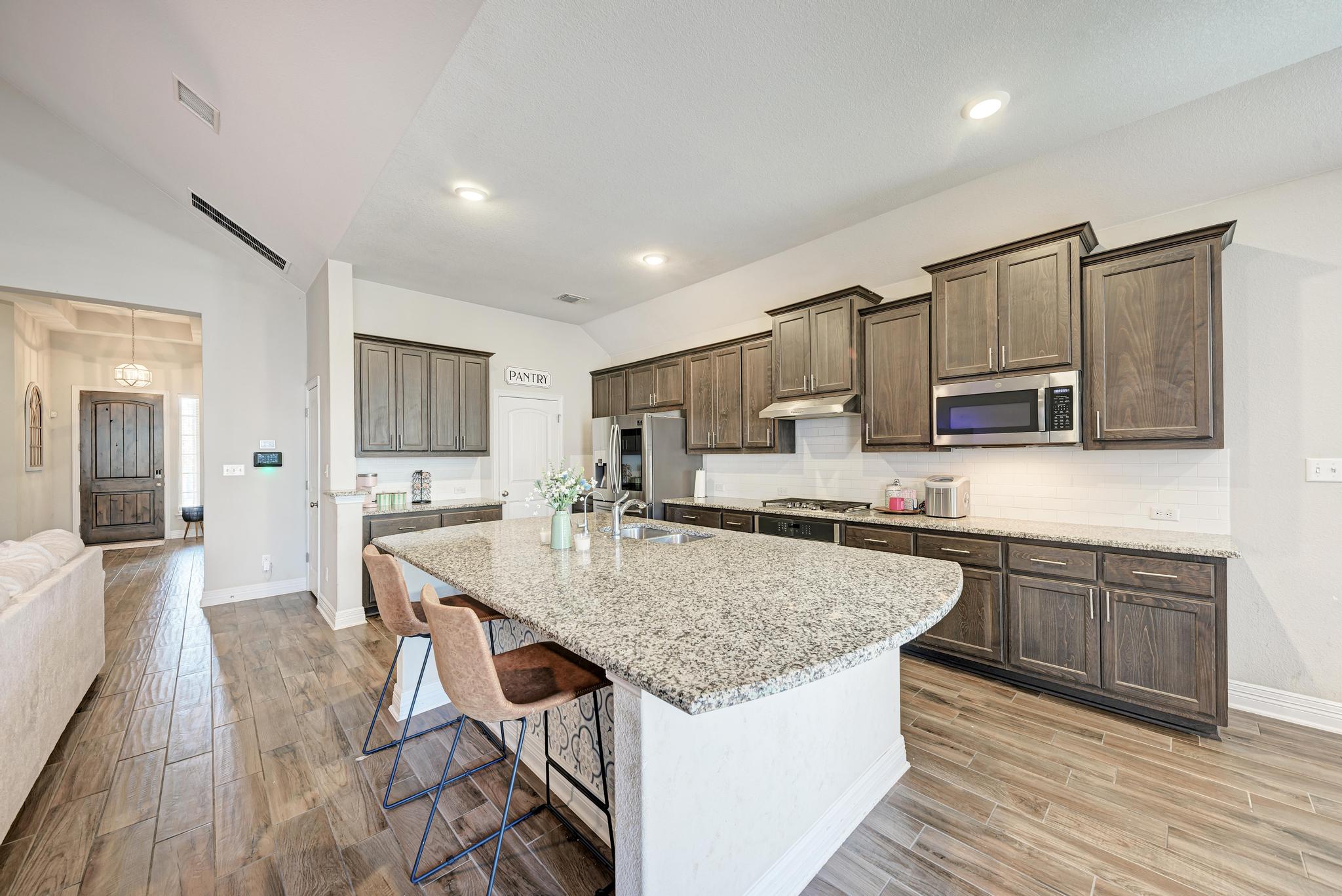 198 Rough Leaf Drive Buda, TX 78610 - Photo 13 of 38 Kitchen featuring light wood finished floors, vaulted ceiling, a kitchen bar, a center island with sink, and stainless steel appliances