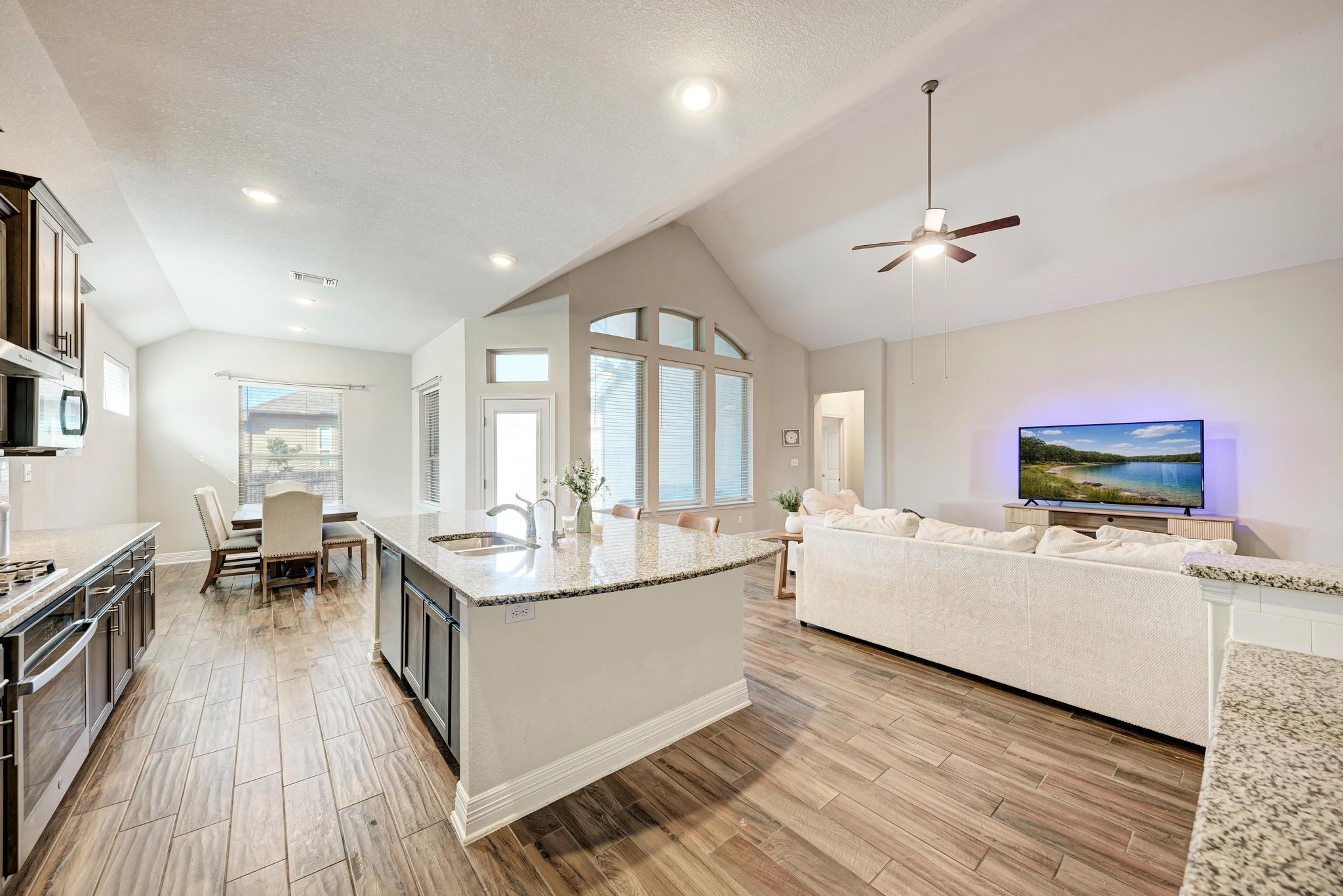 198 Rough Leaf Drive Buda, TX 78610 - Photo 37 of 38 Kitchen with light stone counters, wood tiled floors, open floor plan, a ceiling fan, and a high textured ceiling