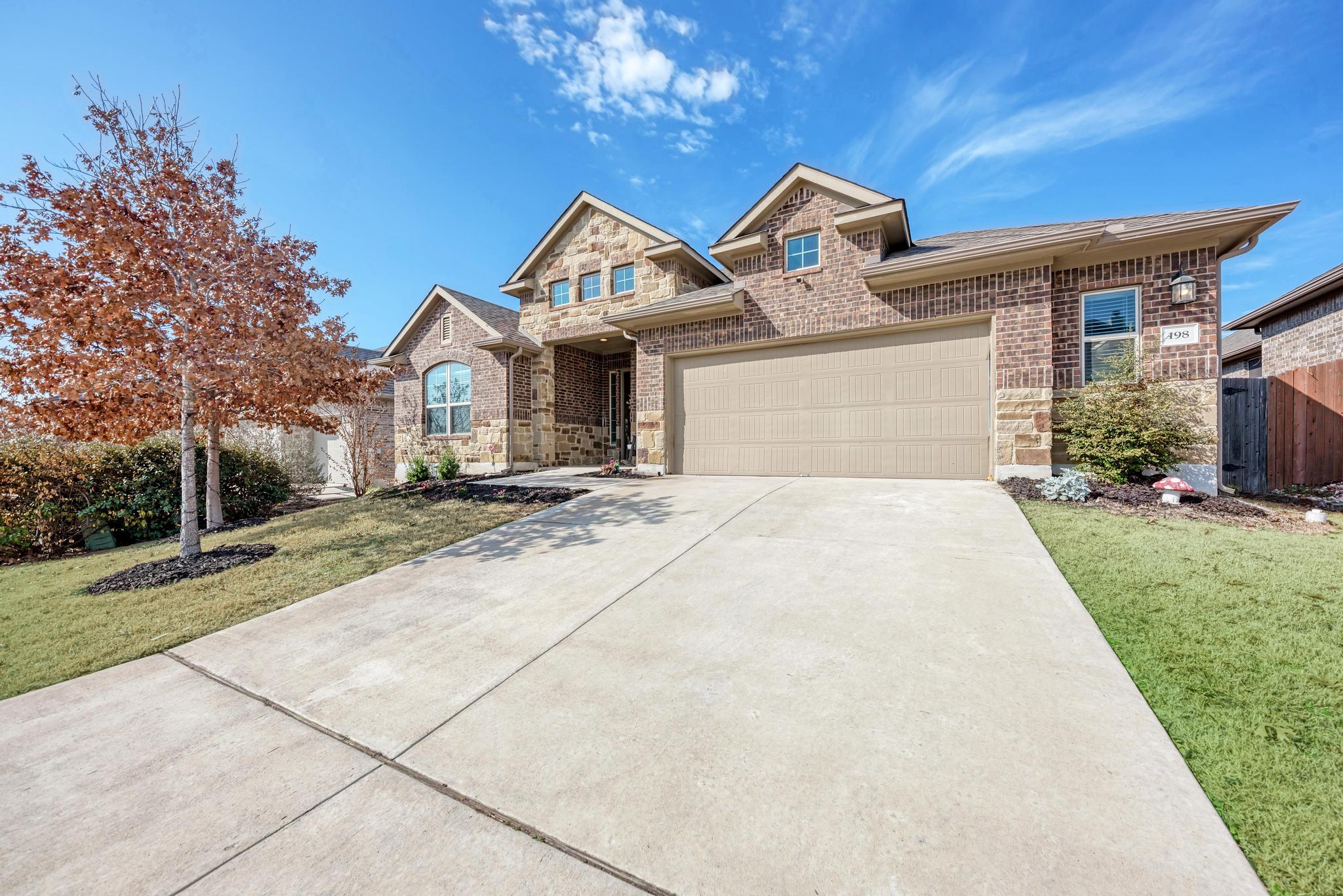 198 Rough Leaf Drive Buda, TX 78610 - Photo 2 of 38 View of front of property featuring brick siding, concrete driveway, stone siding, and a garage