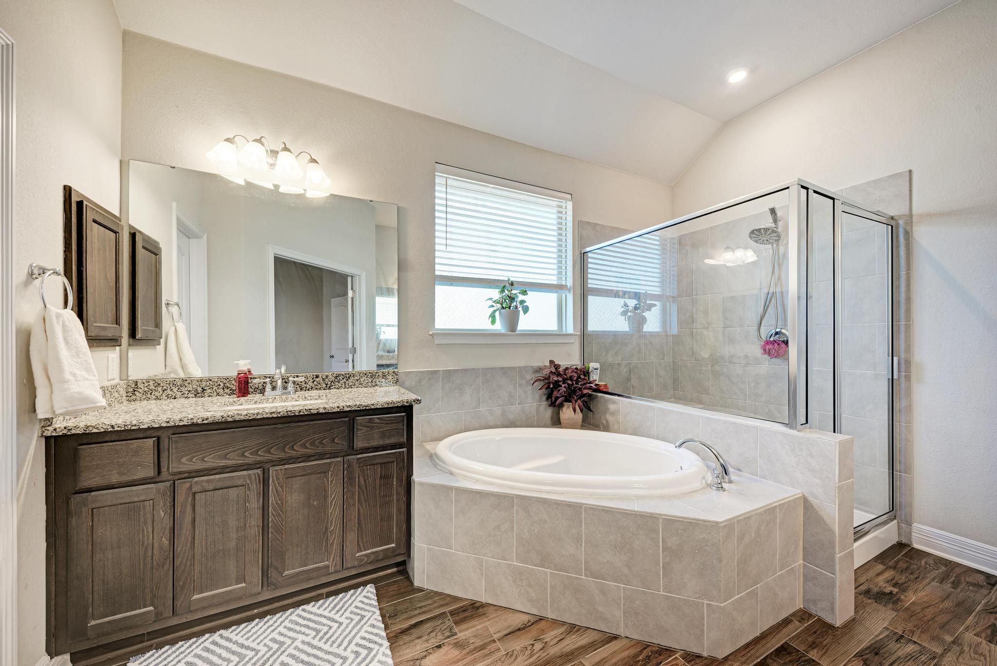 198 Rough Leaf Drive Buda, TX 78610 - Photo 19 of 38 Bathroom with a bath, wood tiled floors, a stall shower, vanity, and lofted ceiling