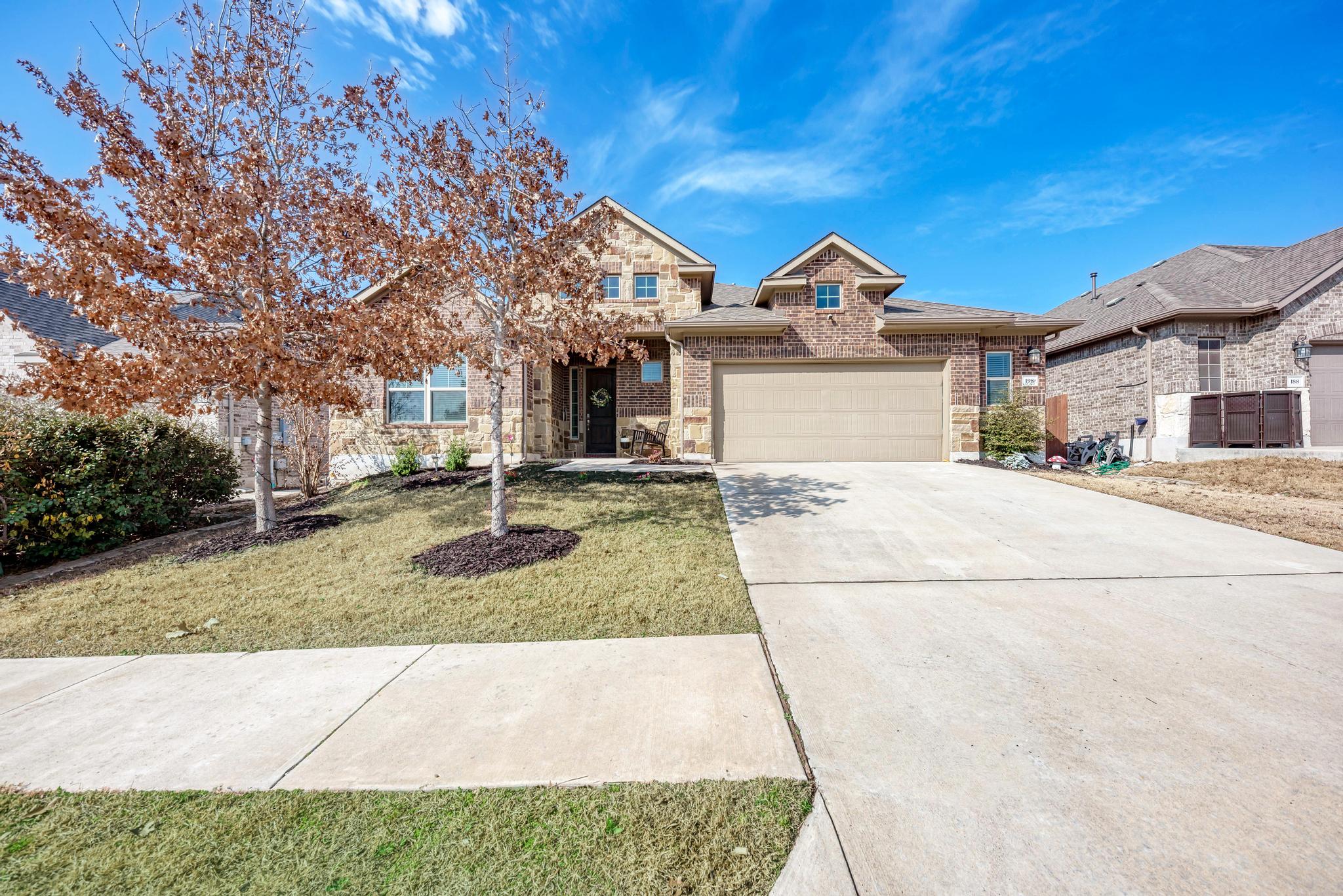 198 Rough Leaf Drive Buda, TX 78610 - Photo 3 of 38 View of front facade featuring concrete driveway, brick siding, a garage, and a front lawn