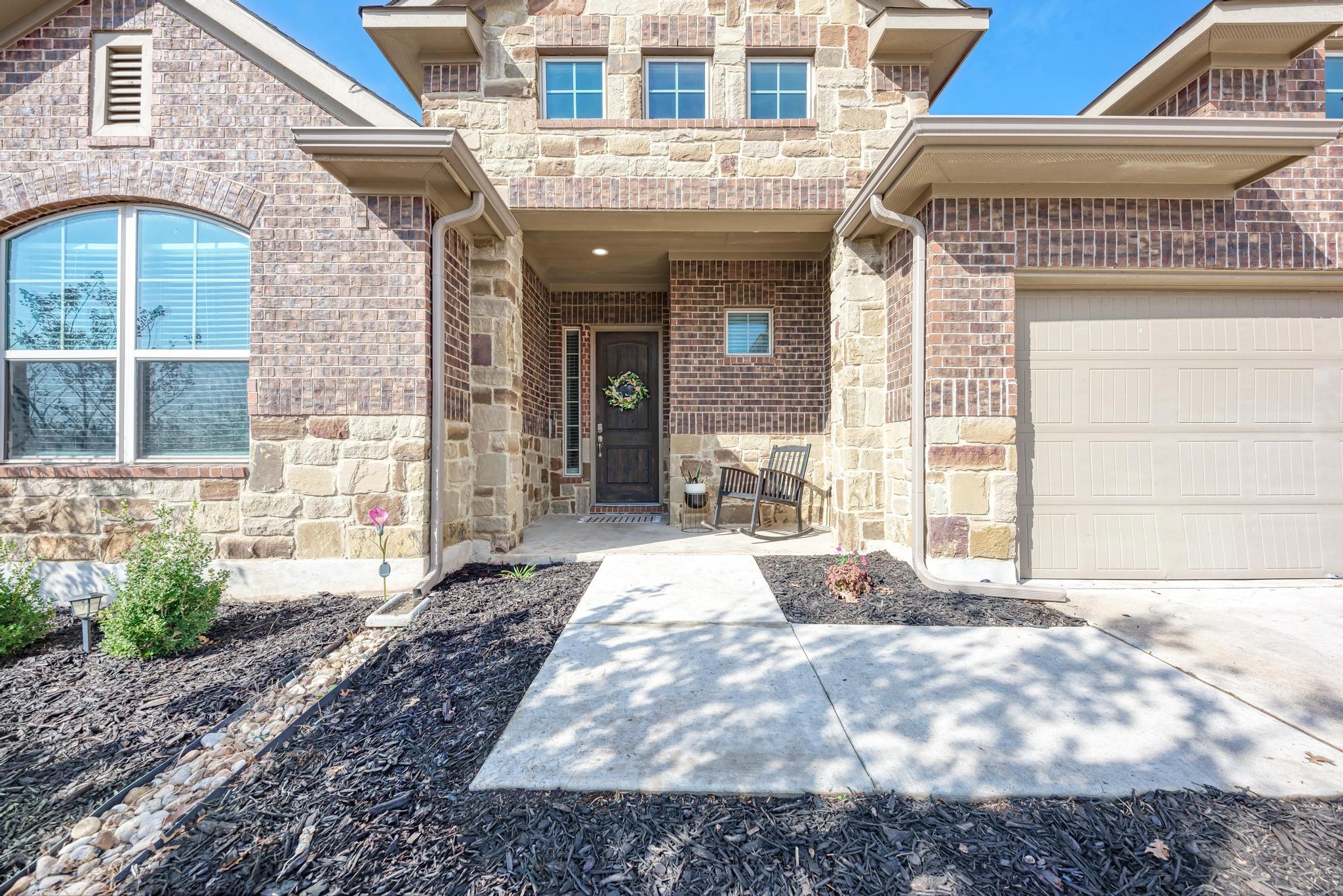 198 Rough Leaf Drive Buda, TX 78610 - Photo 5 of 38 Property entrance with stone siding, a garage, a porch, and driveway