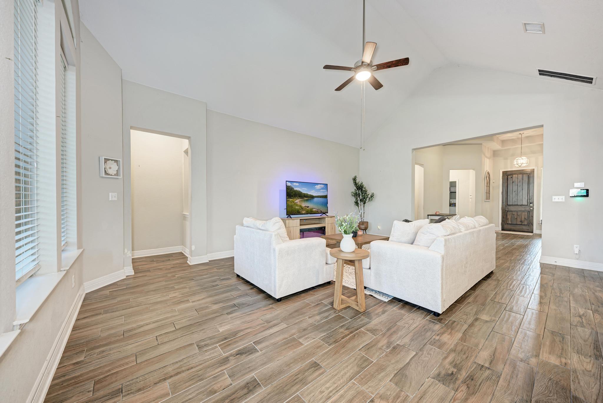 198 Rough Leaf Drive Buda, TX 78610 - Photo 10 of 38 Living room featuring wood tiled floors, a ceiling fan, and a high ceiling