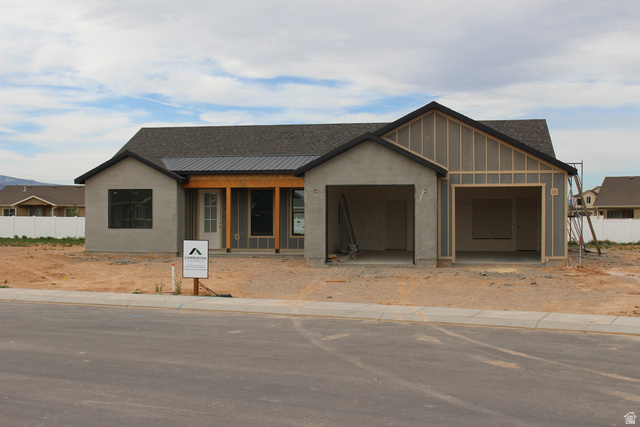 4933 East Remington Road Cedar City, UT 84721 - Photo 33 of 33 Single-story residence featuring a gray exterior finish, a prominent two-car garage, and a covered entry porch with exposed wood beams