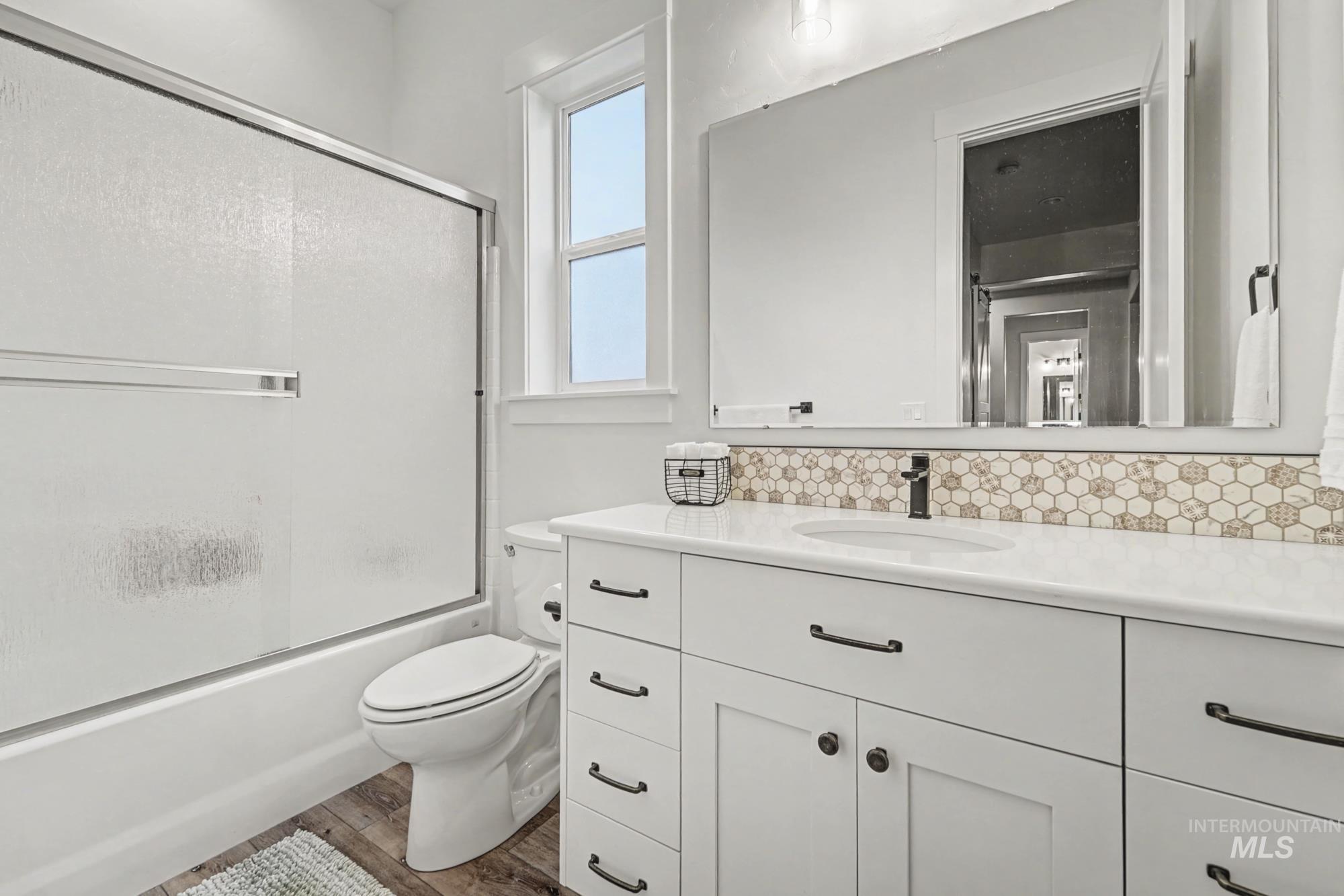 18357 North Burnt Car Way Boise, ID 83714 - Photo 39 of 48 Full bathroom featuring enclosed tub / shower combo, vanity, dark wood-type flooring, and decorative backsplash