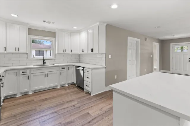 a kitchen with a white cabinets stove and wooden floor
