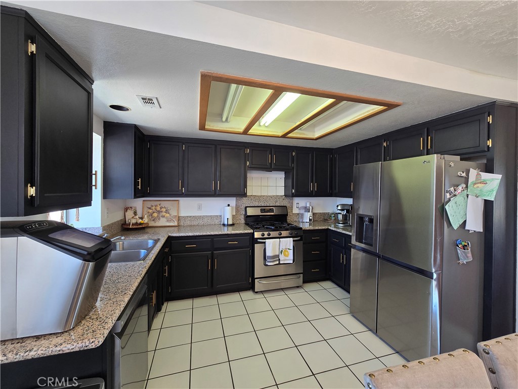 9995 Smoke Tree Road Hesperia, CA 92344 - Photo 3 of 74 a kitchen with stainless steel appliances granite countertop a refrigerator and a stove top oven