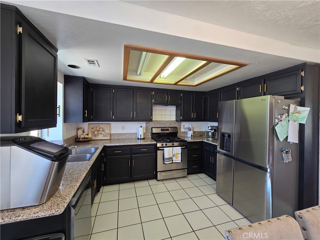 9995 Smoke Tree Road Hesperia, CA 92344 - Photo 35 of 74 a kitchen with stainless steel appliances granite countertop a refrigerator and a stove top oven