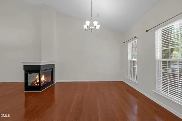 a view of an empty room with wooden floor fireplace and a window