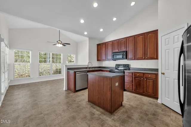 a kitchen with stainless steel appliances granite countertop a refrigerator a sink dishwasher a stove with wooden cabinets and floor