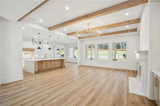 a large white kitchen with a stove a sink dishwasher and a refrigerator with wooden floor