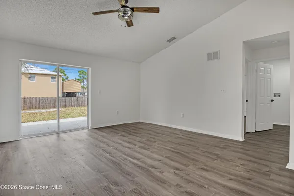 an empty room with wooden floor and windows