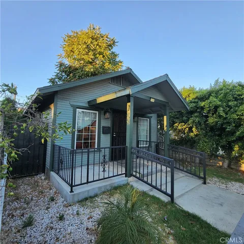 a view of a wooden house with large trees and furniture