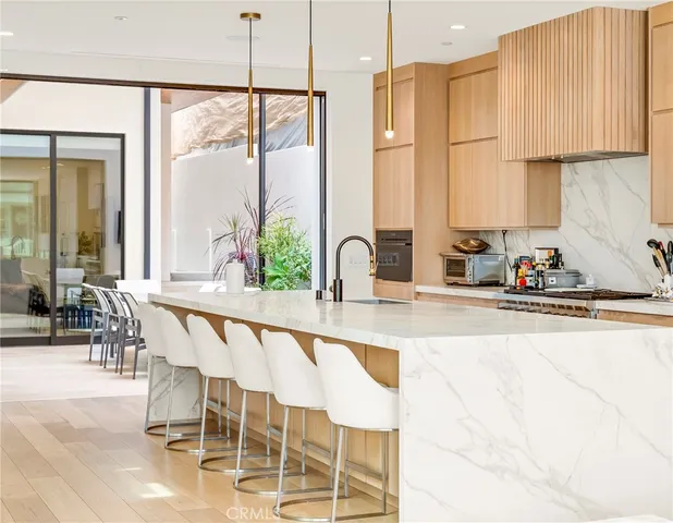 a kitchen with stainless steel appliances kitchen island granite countertop a table chairs and a refrigerator