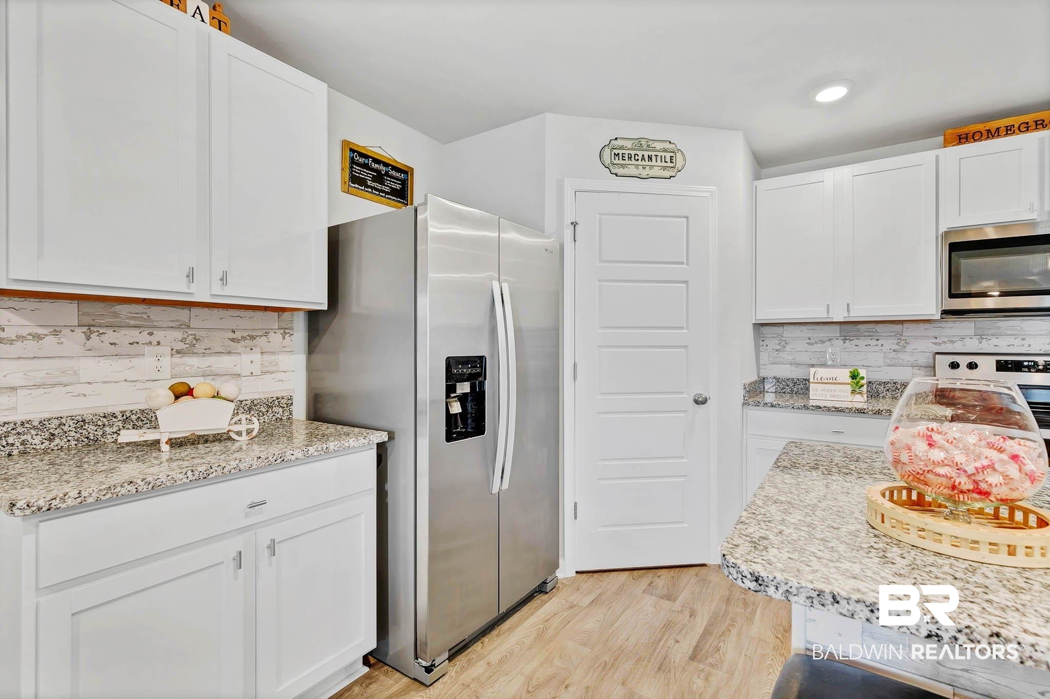 17217 REFLECTION Street Loxley, AL 36551 - Photo 12 of 83 Kitchen featuring stainless steel appliances, white cabinets, backsplash, light wood-style lvp flooring, granite countertops and recessed lighting