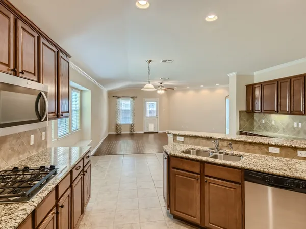 a large kitchen with stainless steel appliances kitchen island granite countertop a refrigerator and stove top oven
