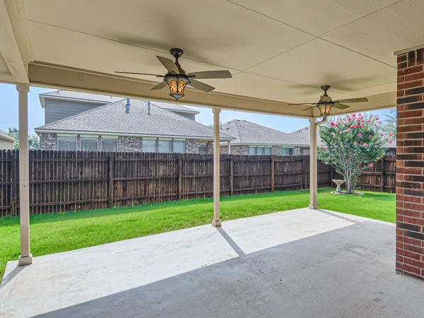 a view of a backyard with wooden fence and a bench