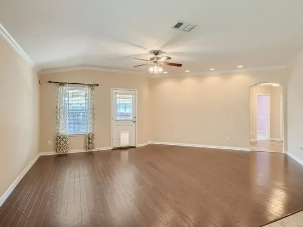 a view of an empty room with window and wooden floor