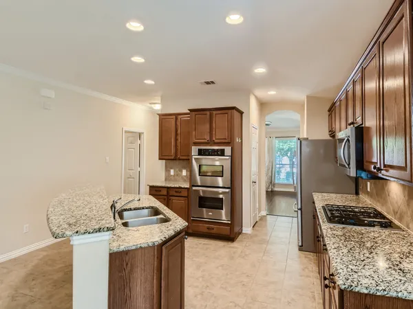 a large kitchen with granite countertop a large counter top stainless steel appliances and cabinets
