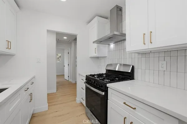 a kitchen with stainless steel appliances a stove a white cabinet and a granite counter tops