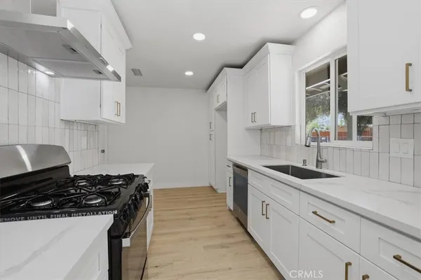 a kitchen with granite countertop a sink stove and cabinets
