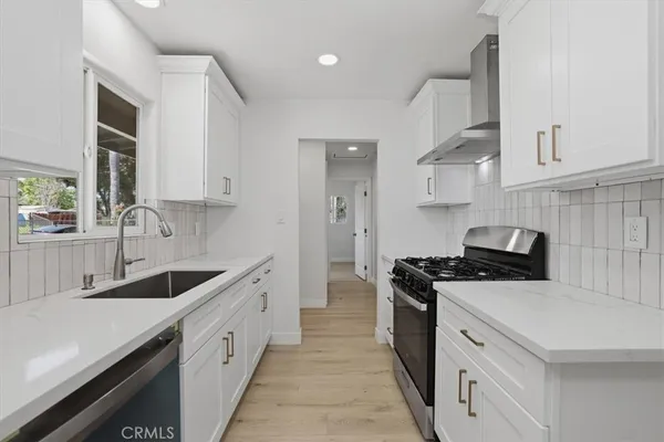 a kitchen with a sink dishwasher a stove and a refrigerator with wooden cabinets