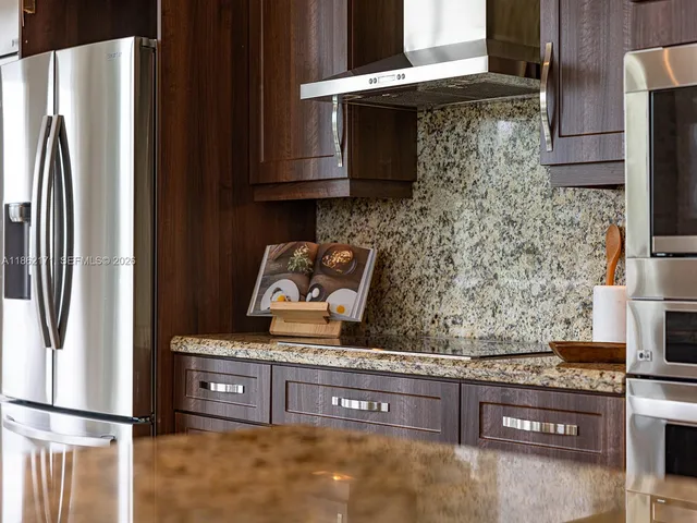 a kitchen with stainless steel appliances granite countertop a refrigerator and a stove